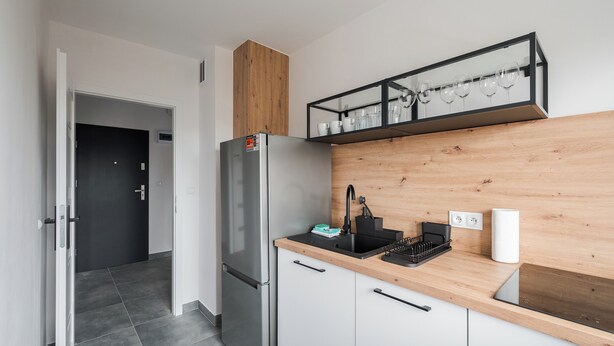 A modern kitchen with a stainless steel refrigerator, a wooden countertop, and a black sink. - Elbląska Modern Apartment (Warszawa)
