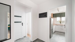 A modern kitchen with white cabinets, a stainless steel refrigerator, and a window with a view. - Elbląska Modern Apartment (Warszawa)