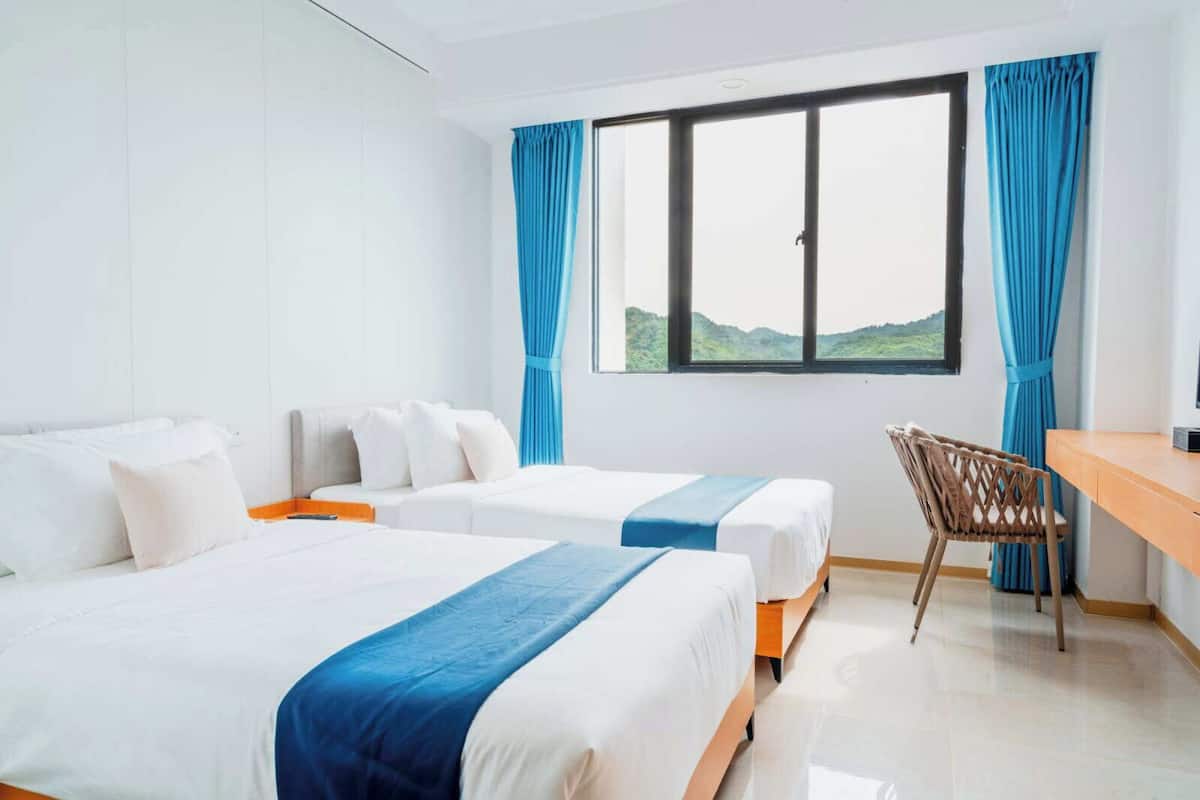 A hotel room with two beds, a desk, and a chair.