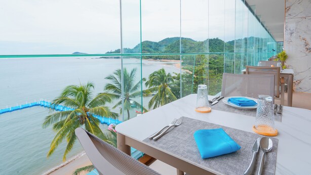 A dining area with a table set for two, overlooking a beach and mountains. - Angel Garden Resort Coron (Busuanga)