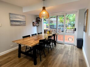 Enjoy meals in this cozy dining area with a long table, pendant light, and garden view.