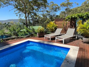 Relax by the serene pool surrounded by lush greenery and comfortable lounge chairs.