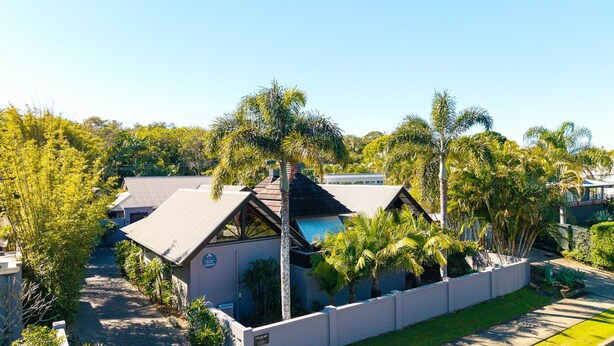 A residential property with a large house, a swimming pool, and lush greenery.