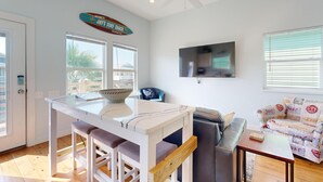 A modern kitchen with a white countertop, bar stools, a ceiling fan, and a large window. - Shared Pool, Golf Cart Access, Pet Friendly (Port Aransas)