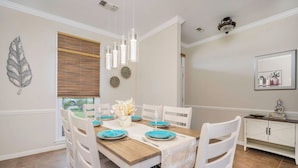A dining room with a wooden table set for four, white chairs, and a decorative wall with a leaf and circular patterns.