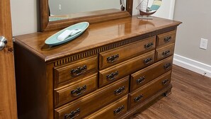 Een houten dressoir met meerdere lades en een grote spiegel erboven.