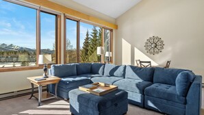 A modern living room with a sectional sofa, a wooden side table, and a decorative wall piece. - L1740-2 (Keystone)