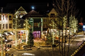 A street view at night with buildings adorned with holiday lights, a visible restaurant, and a clear sidewalk.