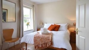 A bedroom with a bed, a chair, a window, and a door. - Central Dingle Townhouse (Dingle)