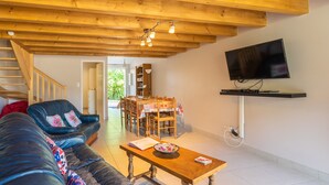 Una sala de estar con sofá, mesa de centro, televisor y comedor con sillas y una mesa.