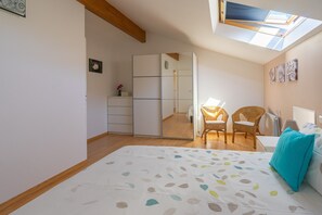 A bedroom with a bed, a wardrobe, a mirror, a window, and a ceiling with wooden beams.