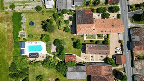 Ett flygbildsbild av ett bostadsområde med en swimmingpool, flera hus med röda tegeltak och en välskött gräsmatta.
