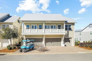 A two-story residential building with a covered garage, a blue golf cart, and a bicycle rack.