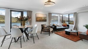 Un salon moderne avec un coin repas, de grandes fenêtres offrant une vue sur les montagnes et un espace salon confortable.