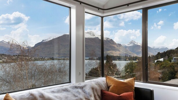 Une pièce dotée d’une grande fenêtre donnant sur un paysage de montagnes et d’un lac.