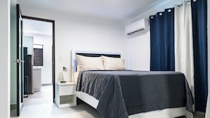 Un dormitorio moderno con cama, mesita de noche y aire acondicionado.