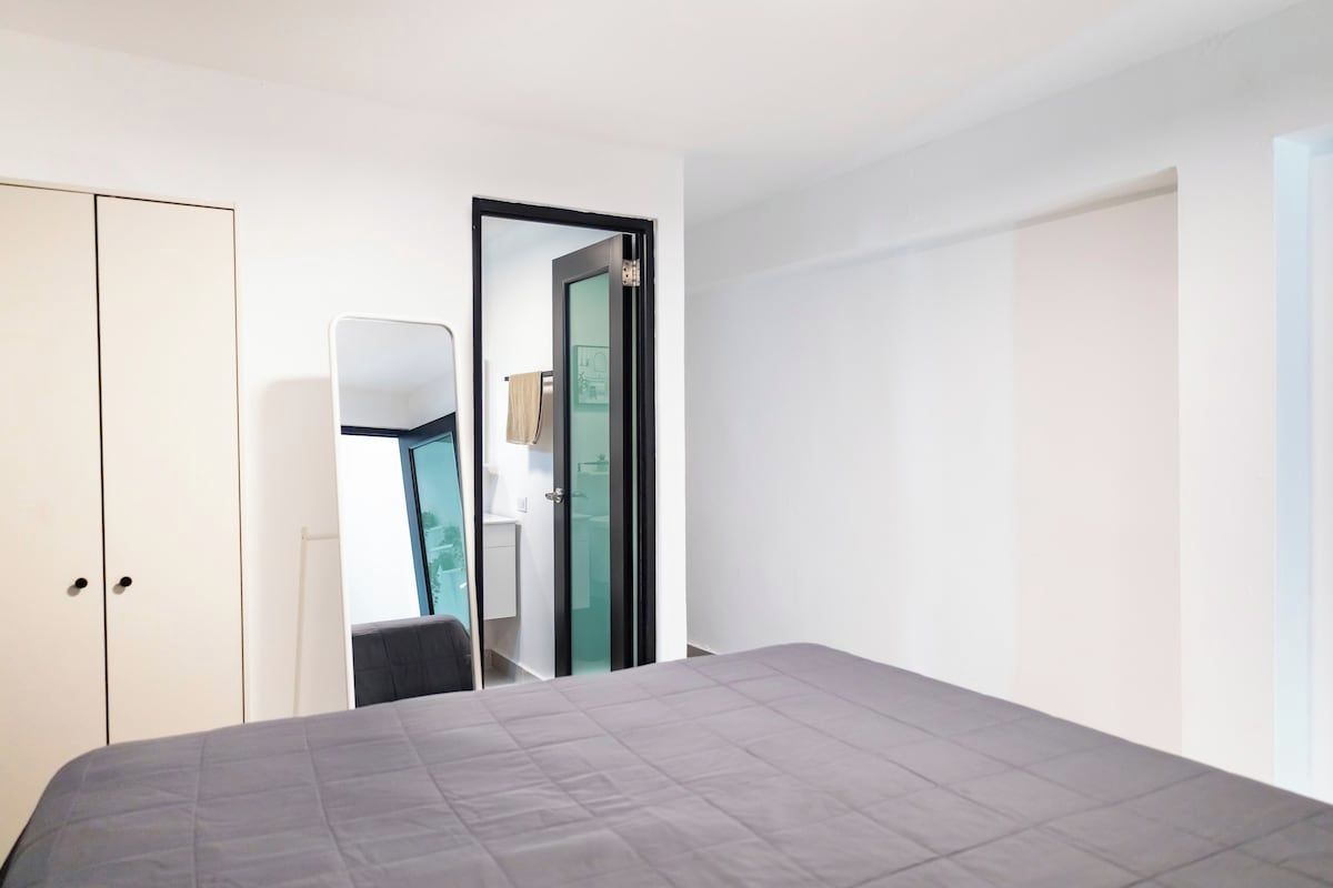 Une chambre à coucher comprenant un lit, une armoire et une porte donnant sur une salle de bain.