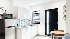 Una cocina moderna con armarios blancos, encimera de mármol, microondas y lavabo.