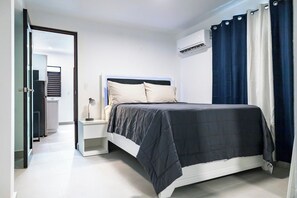 Ein Schlafzimmer mit Bett, Nachttisch, Lampe und Klimaanlage.