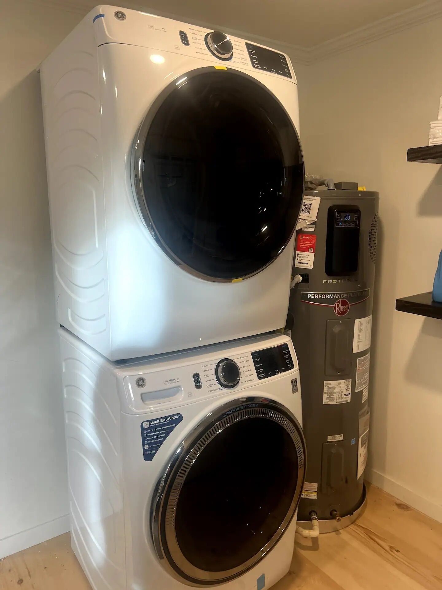 Una lavadora y secadora apiladas, con un panel de control, un calentador de agua y un termostato.