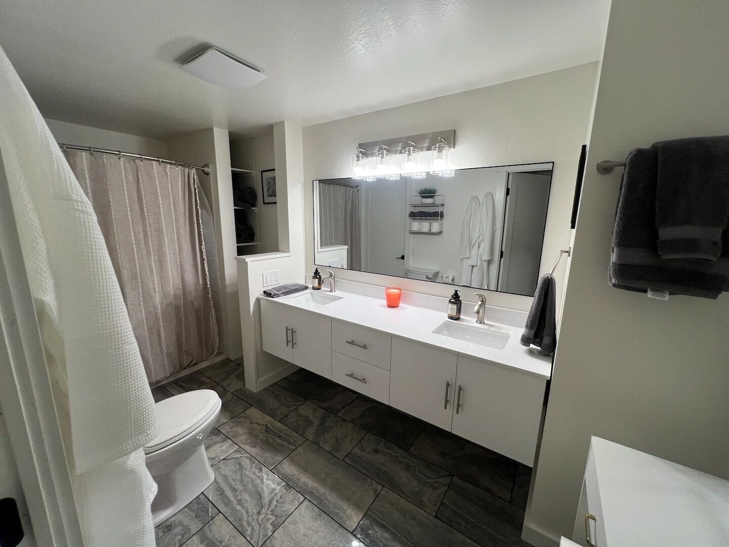 A modern bathroom with a white sink, mirror, and toilet.