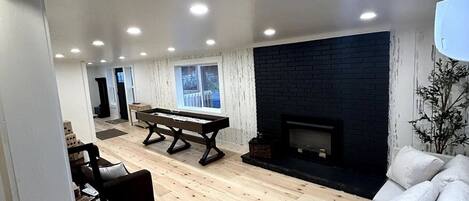 Un salón amplio con suelo de madera, una chimenea, un sofá y una mesa de comedor.
