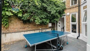 A ping pong table in an outdoor area with a brick wall and greenery. - Stylish 2 Bedroom / 2 Bath in Notting Hill (London)