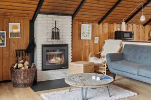 A cozy living room with a fireplace, wicker furniture, a blue sofa, and a round coffee table.