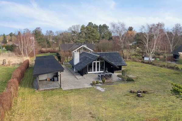 A house with a large garage, a covered outdoor seating area, and a well-maintained lawn.