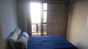 Ein Schlafzimmer mit einem Bett, einem Fenster und Vorhängen.