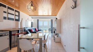 Una cucina moderna con zona pranzo, soffitto in legno e ampie finestre.