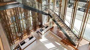 A modern interior with a glass staircase, wooden railings, and a reception desk. - Wyndham Vacation Resort Downtown ATL walking distance to MercedesBenz Stadium (Atlanta)