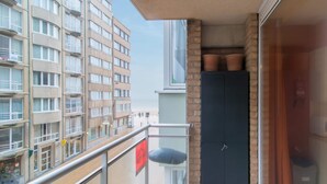 Un balcone con ringhiera in metallo, una porta scura e vista su un edificio di un hotel sullo sfondo.