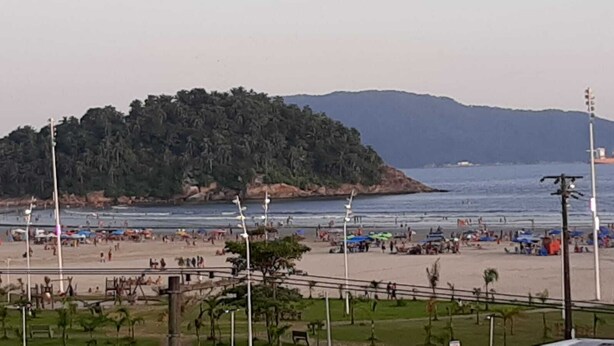 Una spiaggia con un'isola boscosa sullo sfondo, una riva sabbiosa e ombrelloni.