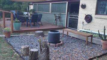 A patio area with a wooden deck, outdoor furniture, and a fire pit.
