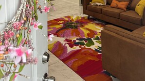 Una sala de estar con un sofá marrón, una alfombra colorida y un ventilador de techo.