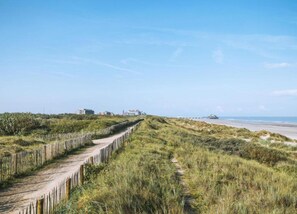 A coastal path with a wooden fence, grassy dunes, and buildings in the distance. - Flat in Blankenberge Near Belgium Pier (Blankenberge)