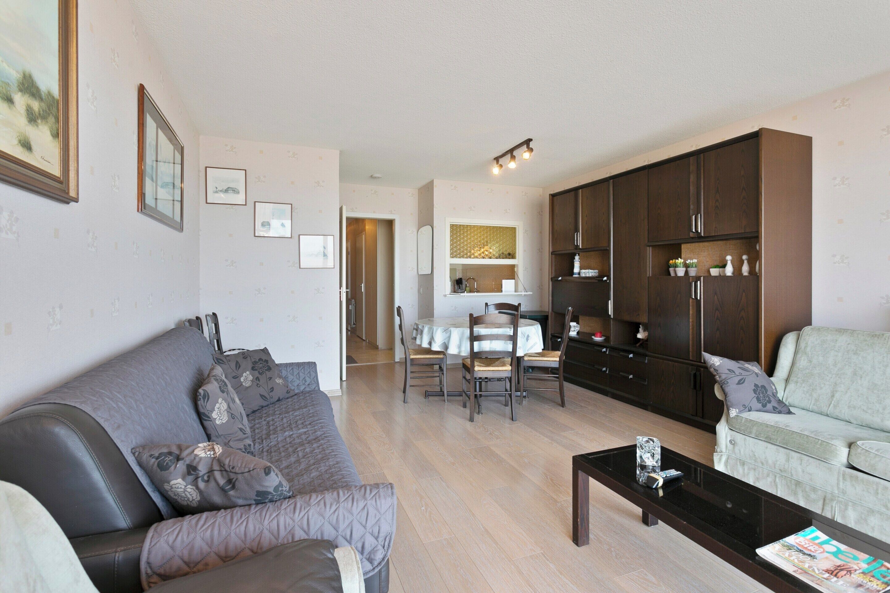 A living room with a sofa, a coffee table, and a dining area with a table and chairs.