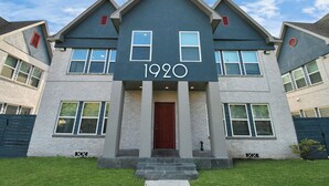 A modern two-story building with a prominent '1920' sign above the entrance, large windows, and a red door. - Serenity Studios: Near Medical Center & Museum District (Houston)