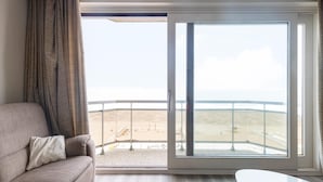 Una stanza con un'ampia finestra vista spiaggia e un balcone con ringhiera.