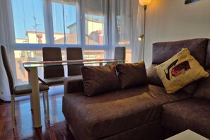 Un salon avec un canapé marron, une table basse en verre et deux fauteuils.