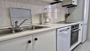Una cocina con un lavamanos de acero inoxidable, una cafetera, una estufa y un lavavajillas.