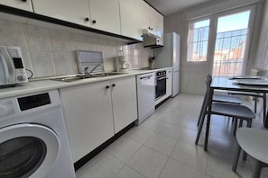 Une cuisine moderne équipée d’un lave-linge, d’une machine à café et d’un coin repas avec des chaises.