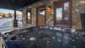 A stone exterior with a hot tub and a wooden door.