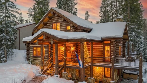 A log cabin with a wooden exterior, a porch, and a staircase leading to the entrance.
