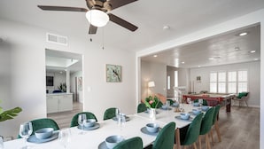 A dining area with a white table set for six, green chairs, and a pool table in the background. - Vegas Luxe- 6BR & 3 BT pool/spa/bbq/golf<10min to Strip, Airport, Stadium & More (Las Vegas)