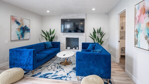 A modern living room with blue sofas, a white coffee table, and a fireplace. - Vegas Luxe- 6BR & 3 BT pool/spa/bbq/golf<10min to Strip, Airport, Stadium & More (Las Vegas)