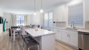 Une cuisine moderne avec des meubles blancs, un îlot central et des tabourets de bar.