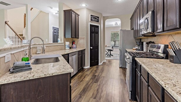 Una cocina moderna con alacenas de madera oscura, encimeras de granito y electrodomésticos de acero inoxidable, además de una isla central.