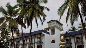 A hotel with multiple floors, balconies, and a sign indicating amenities like a bar, salon, spa, gym, and pool. - The Upper House By Mystical Views (Morjim)